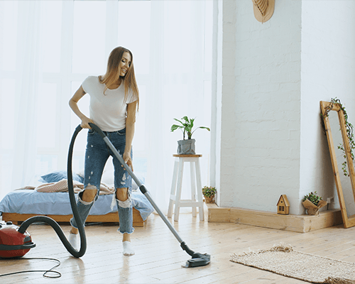Photo of a woman cleaning a home with a vacuum cleaner
